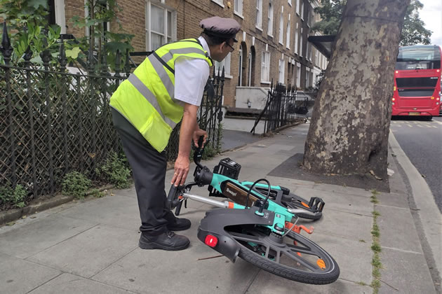 An enforcement officer moving an e-bike obstructing the pavement
